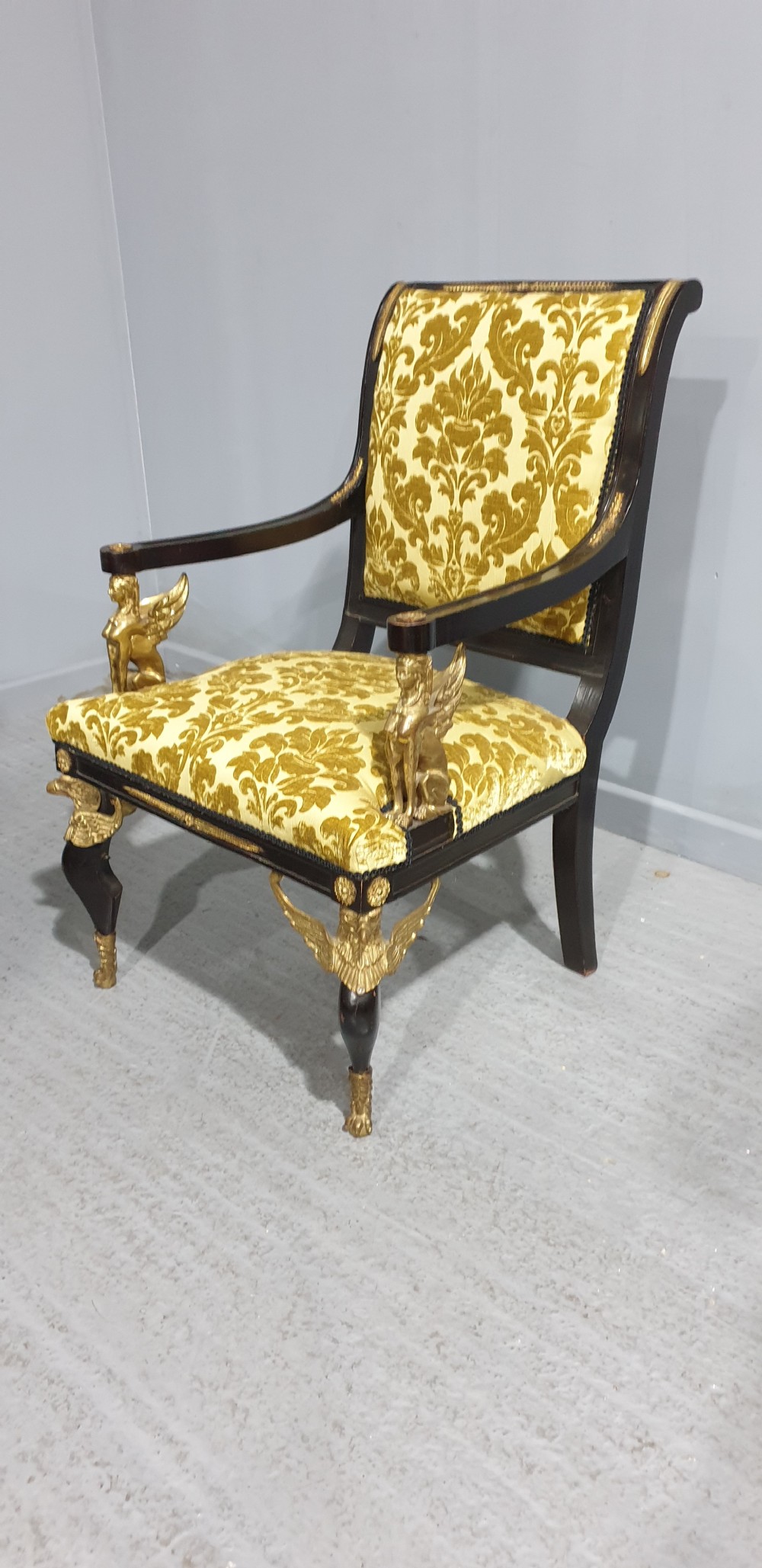 A pair of French Empire armchairs crafted with dark ebonised frames, gilded ormolu caryatid mounts, and patterned gold damask upholstery. View VI