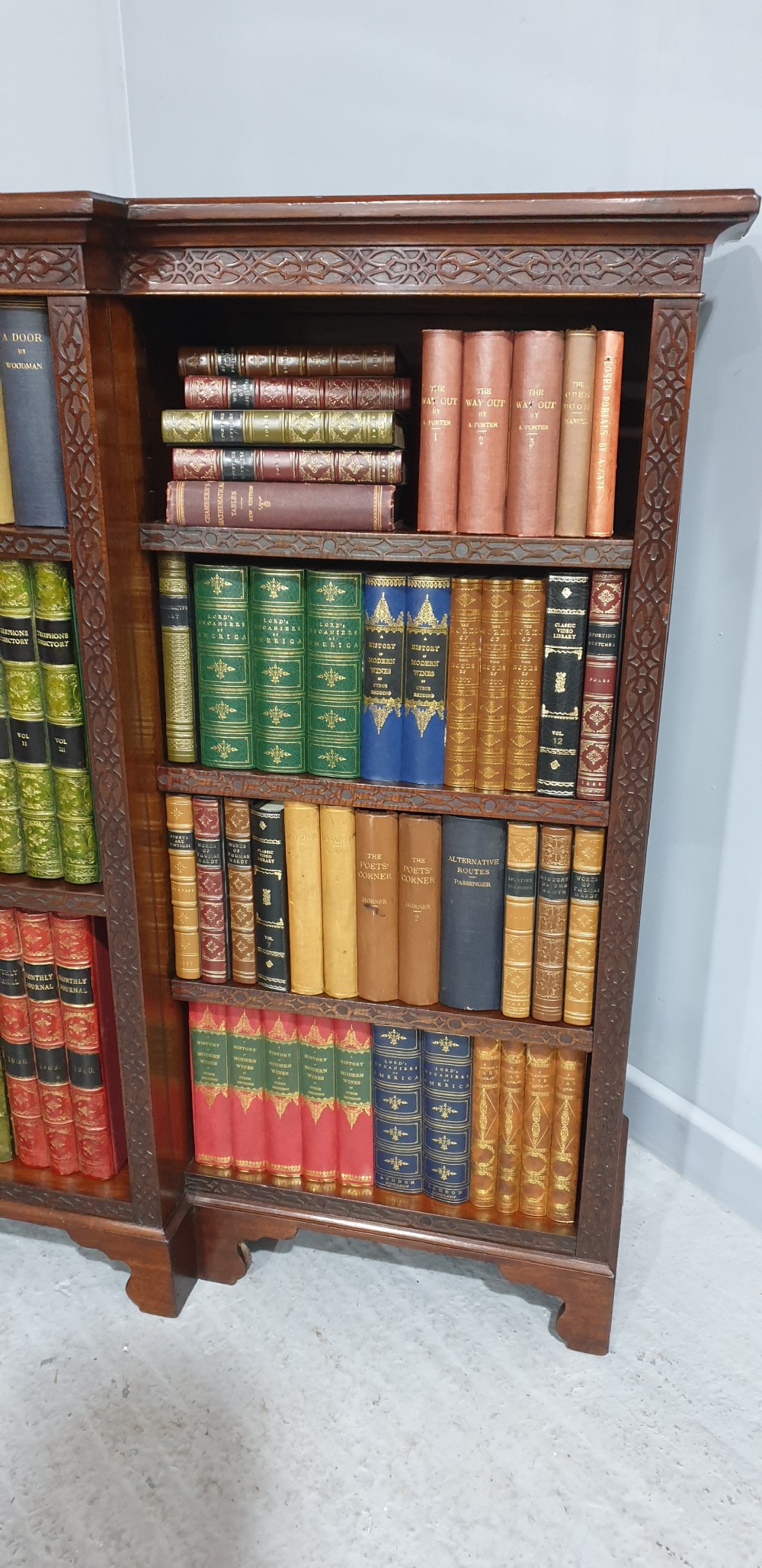 A low, wide mahogany breakfront open bookcase featuring three sections of adjustable shelves with carved fretwork detail along the top edge. View II