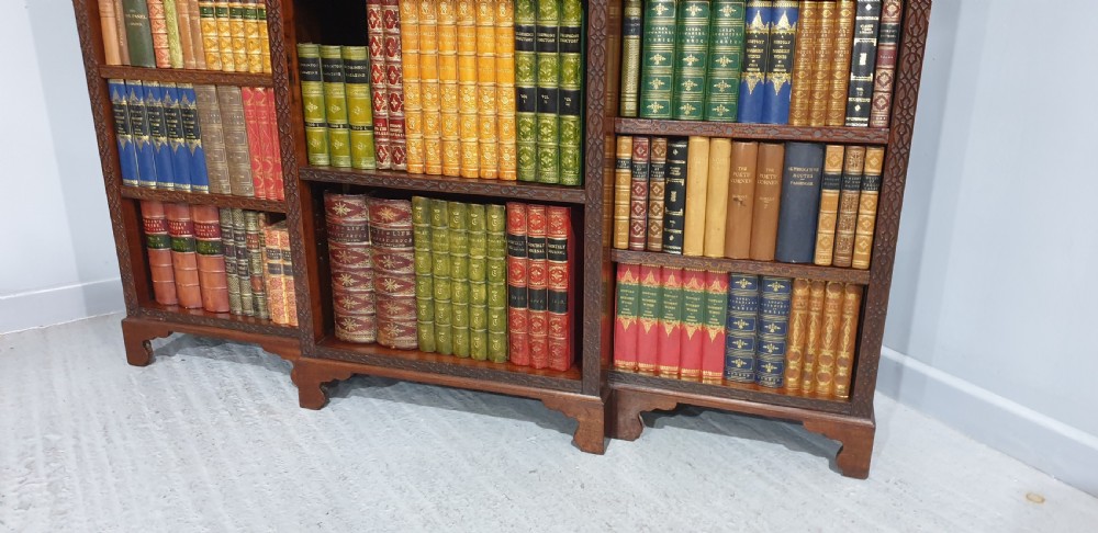 A low, wide mahogany breakfront open bookcase featuring three sections of adjustable shelves with carved fretwork detail along the top edge. View V