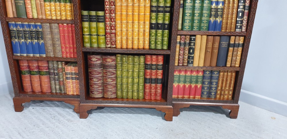 A low, wide mahogany breakfront open bookcase featuring three sections of adjustable shelves with carved fretwork detail along the top edge. View VI