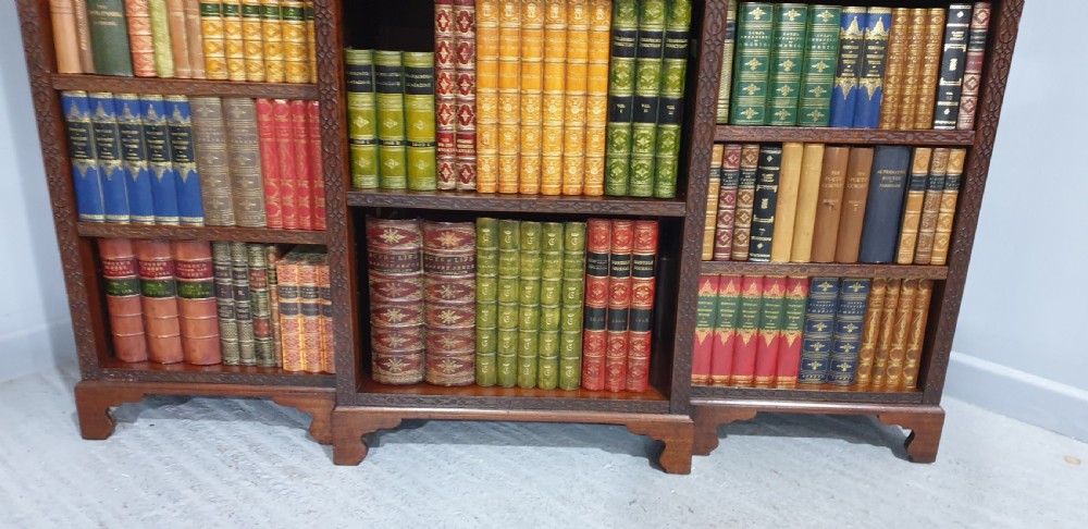 A low, wide mahogany breakfront open bookcase featuring three sections of adjustable shelves with carved fretwork detail along the top edge. View VII