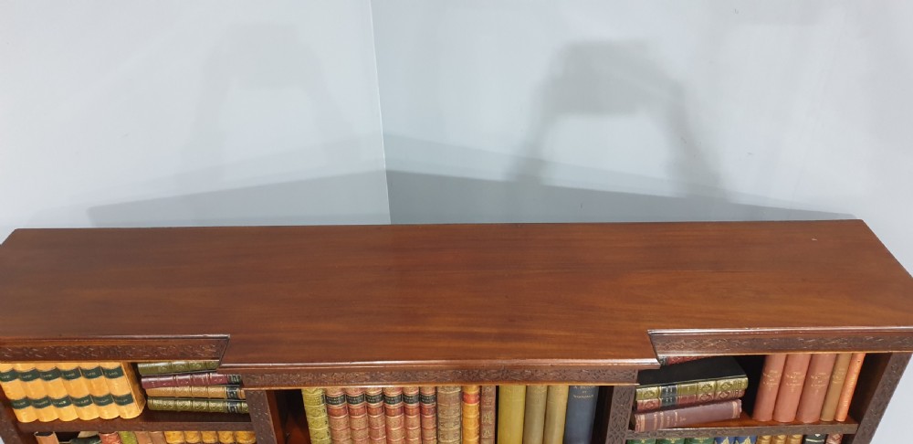 A low, wide mahogany breakfront open bookcase featuring three sections of adjustable shelves with carved fretwork detail along the top edge. View IX