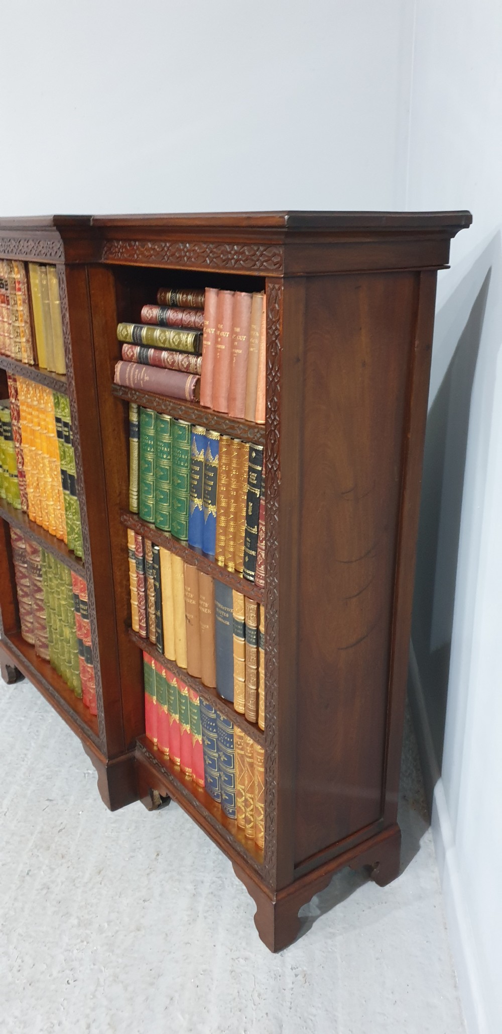 A low, wide mahogany breakfront open bookcase featuring three sections of adjustable shelves with carved fretwork detail along the top edge. View XI