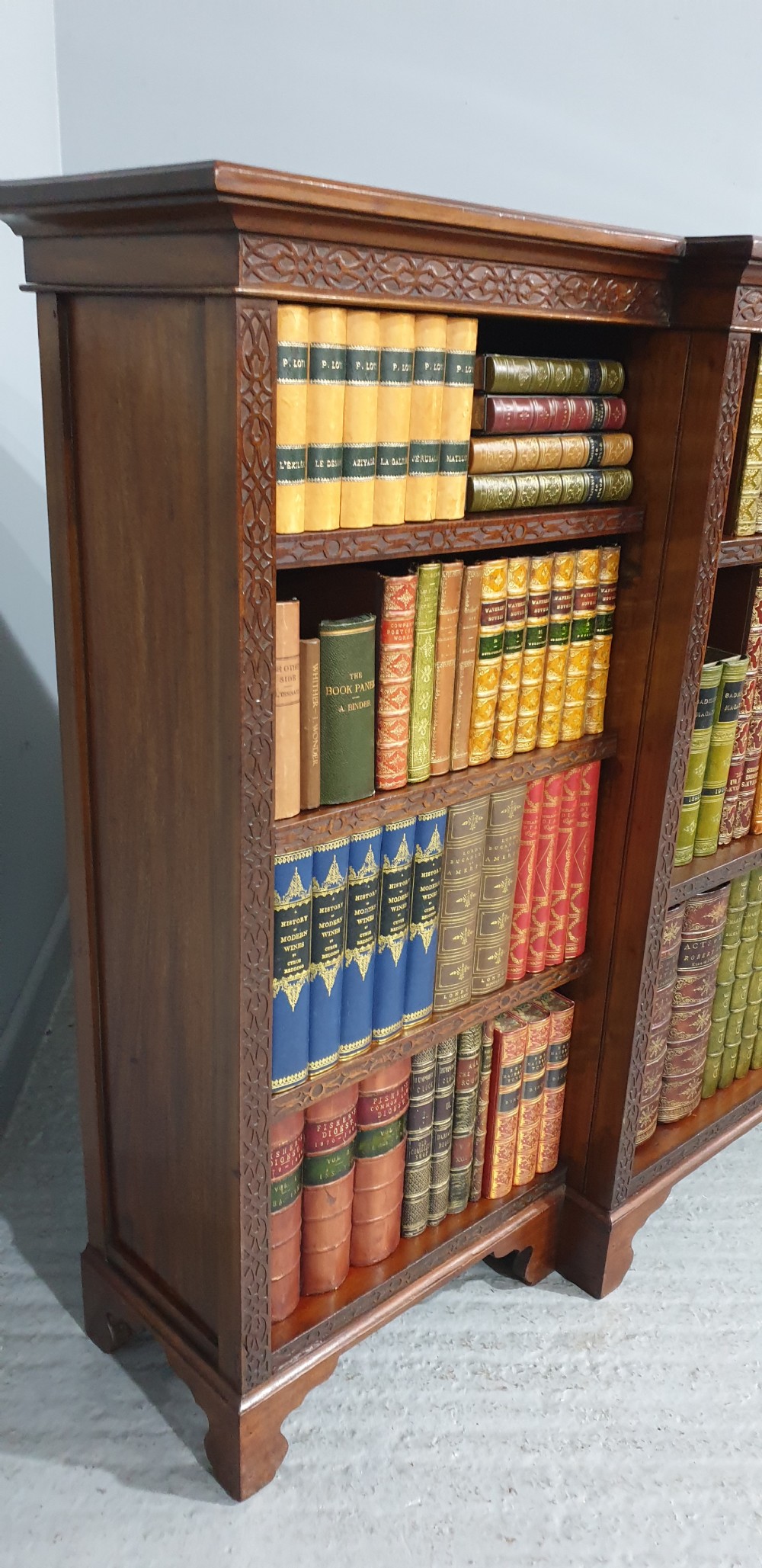 A low, wide mahogany breakfront open bookcase featuring three sections of adjustable shelves with carved fretwork detail along the top edge. View XII