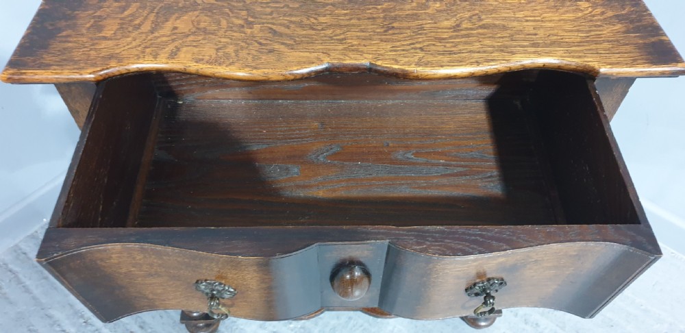 An antique oak side table featuring bobbin turned legs, a shaped frieze drawer with brass drop handles, and a wavy cross-stretcher base. View VIII