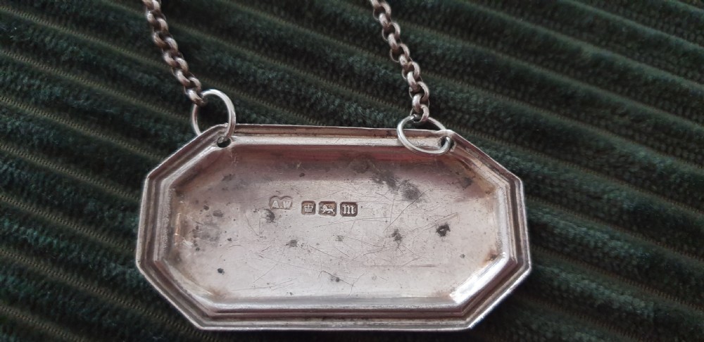 A set of three octagonal silver decanter labels with fine link chains, engraved with Brandy, Irish Whisky, and Scotch Whisky in Gothic script. View VI