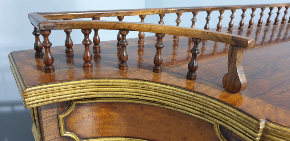 A Regency rosewood side cabinet featuring a spindle gallery rail, gilt brass trim, upper drawers, and fabric panel doors with brass lattice. View XII