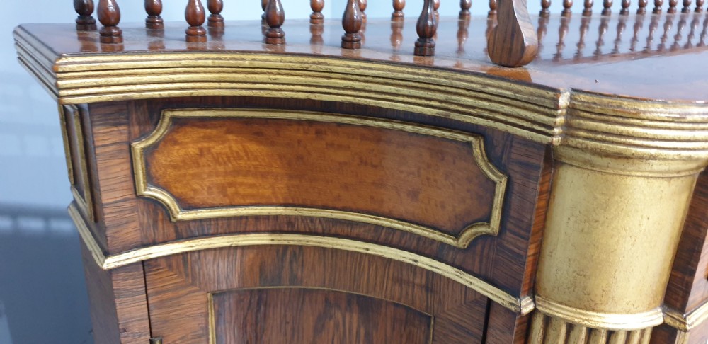 A Regency rosewood side cabinet featuring a spindle gallery rail, gilt brass trim, upper drawers, and fabric panel doors with brass lattice. View XIII