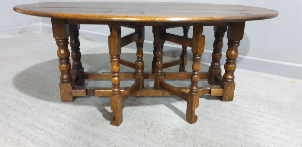 A low solid oak oval coffee table featuring turned gateleg supports and a warm brown timber patina. View II