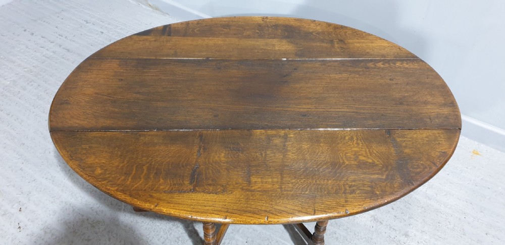 A low solid oak oval coffee table featuring turned gateleg supports and a warm brown timber patina. View V