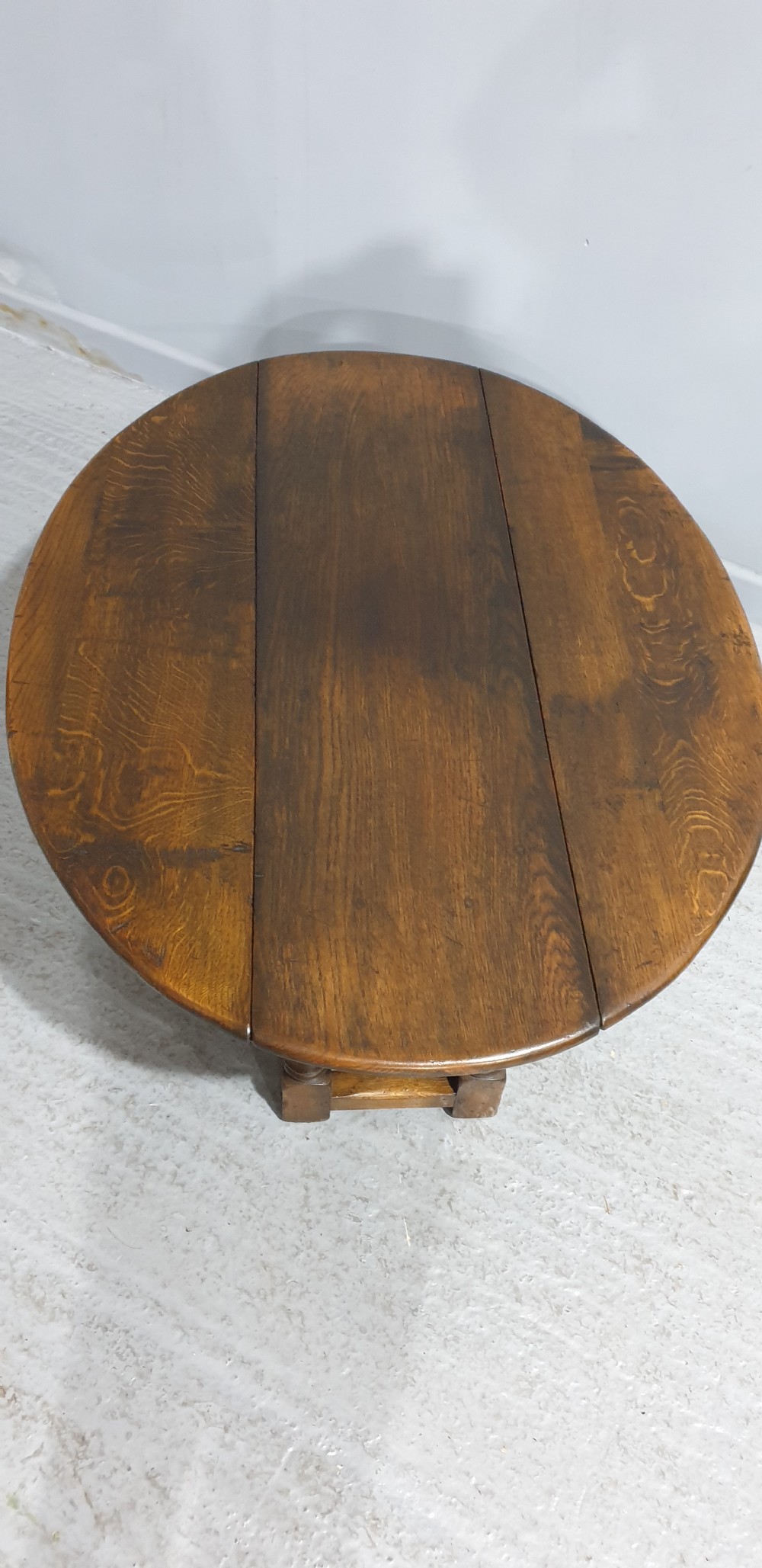 A low solid oak oval coffee table featuring turned gateleg supports and a warm brown timber patina. View VI