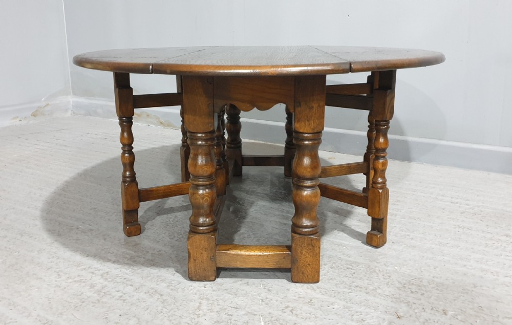 A low solid oak oval coffee table featuring turned gateleg supports and a warm brown timber patina. View VIII