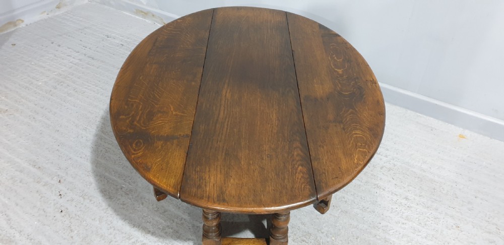 A low solid oak oval coffee table featuring turned gateleg supports and a warm brown timber patina. View IX