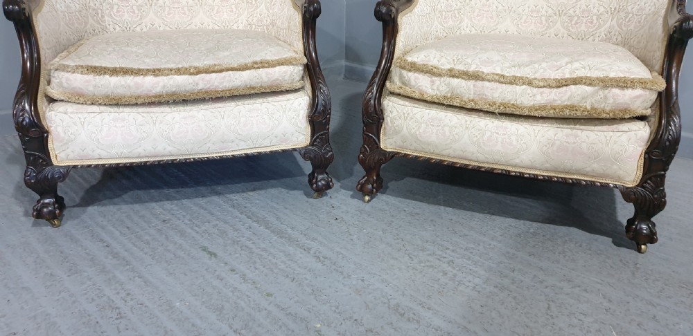 A pair of Victorian mahogany hoop-backed easy chairs upholstered in cream patterned damask fabric with carved legs on brass castors. View IV