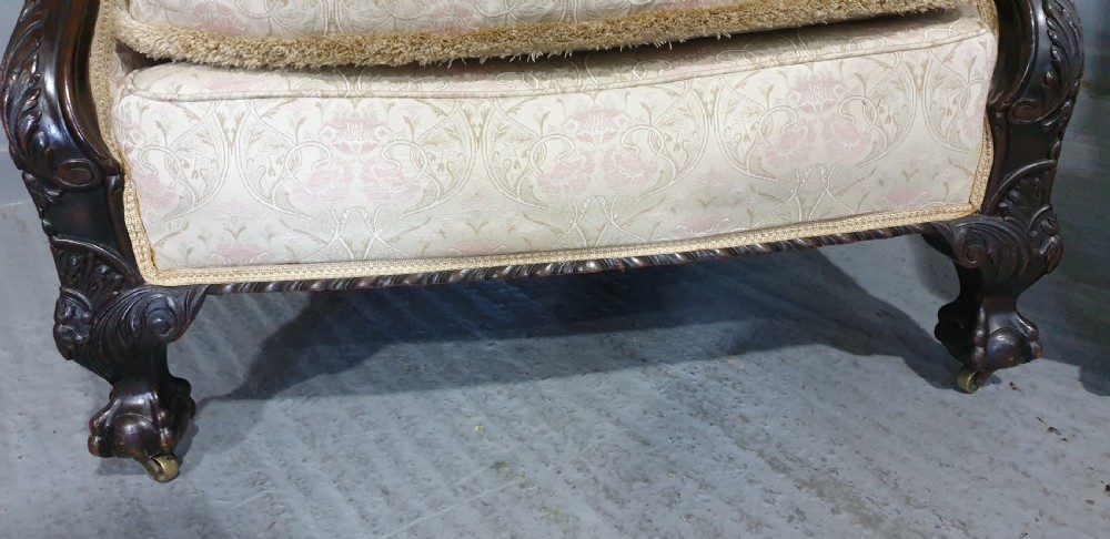 A pair of Victorian mahogany hoop-backed easy chairs upholstered in cream patterned damask fabric with carved legs on brass castors. View V
