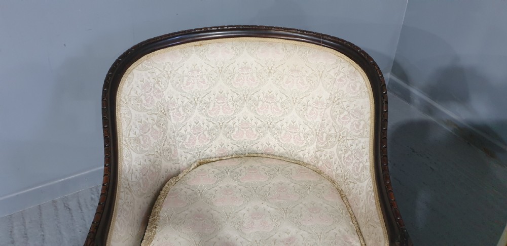 A pair of Victorian mahogany hoop-backed easy chairs upholstered in cream patterned damask fabric with carved legs on brass castors. View VI