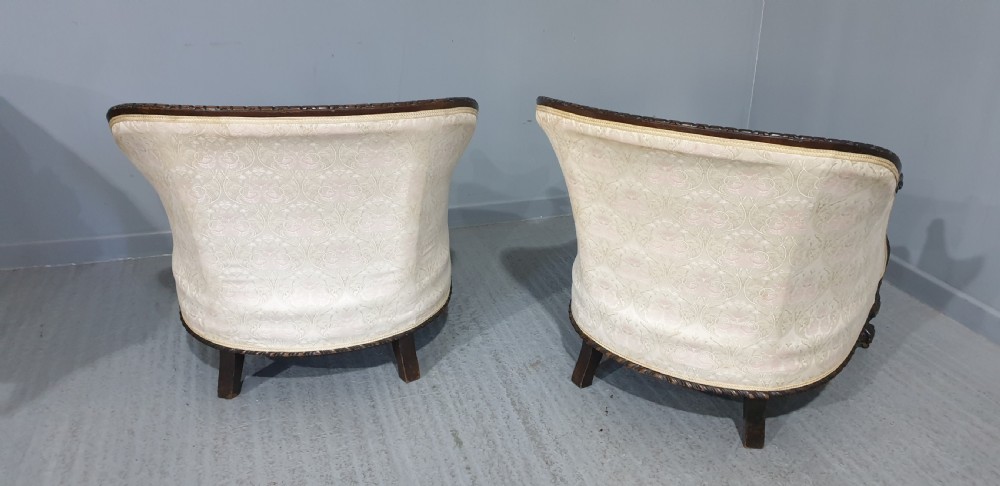 A pair of Victorian mahogany hoop-backed easy chairs upholstered in cream patterned damask fabric with carved legs on brass castors. View XI