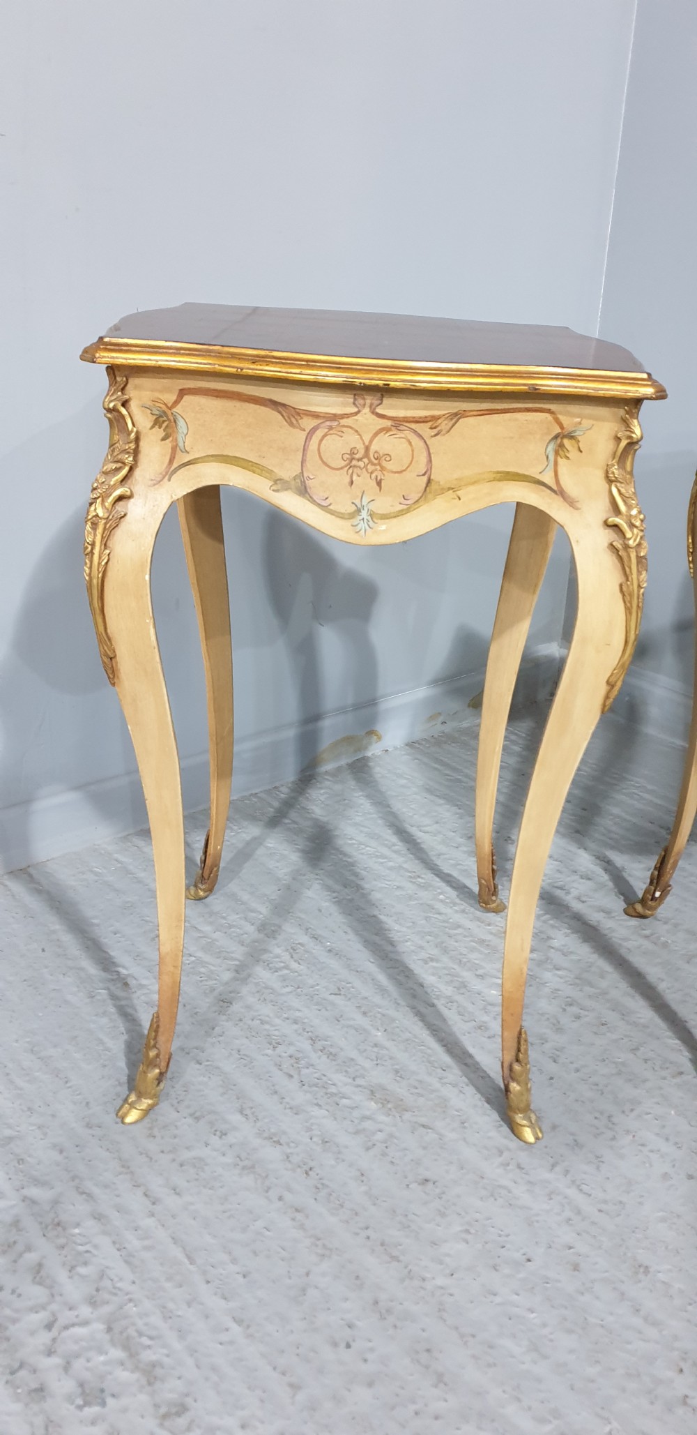 A pair of French Louis XV style tall side tables featuring cream painted cabriole legs with gilt carved embellishments and wooden tops. View II