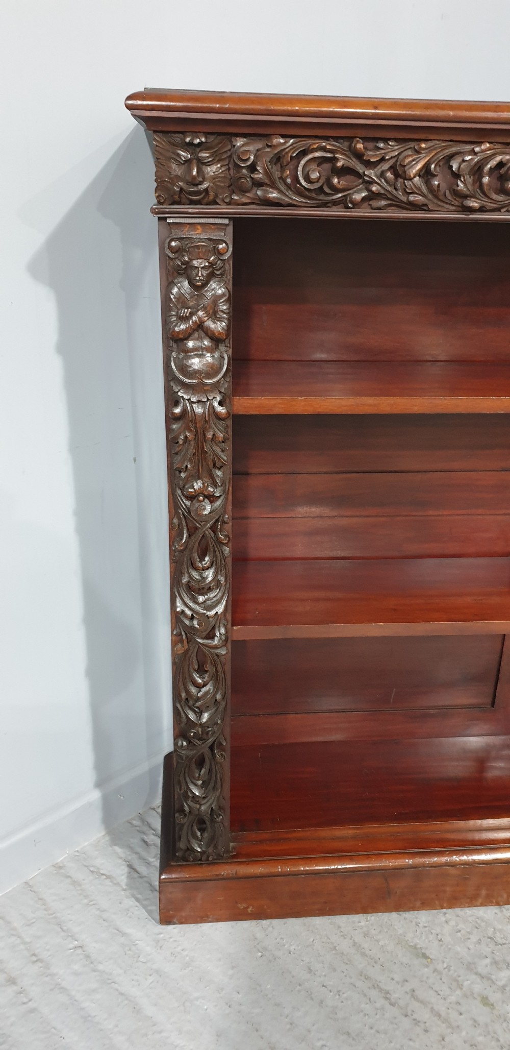 A pair of low mahogany open library bookcases featuring carved friezes, pilasters, and three adjustable shelves on plinth bases. View V