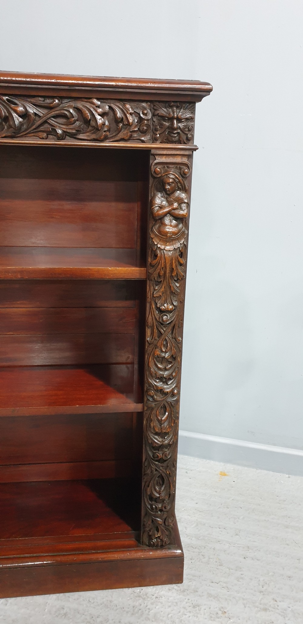 A pair of low mahogany open library bookcases featuring carved friezes, pilasters, and three adjustable shelves on plinth bases. View VI