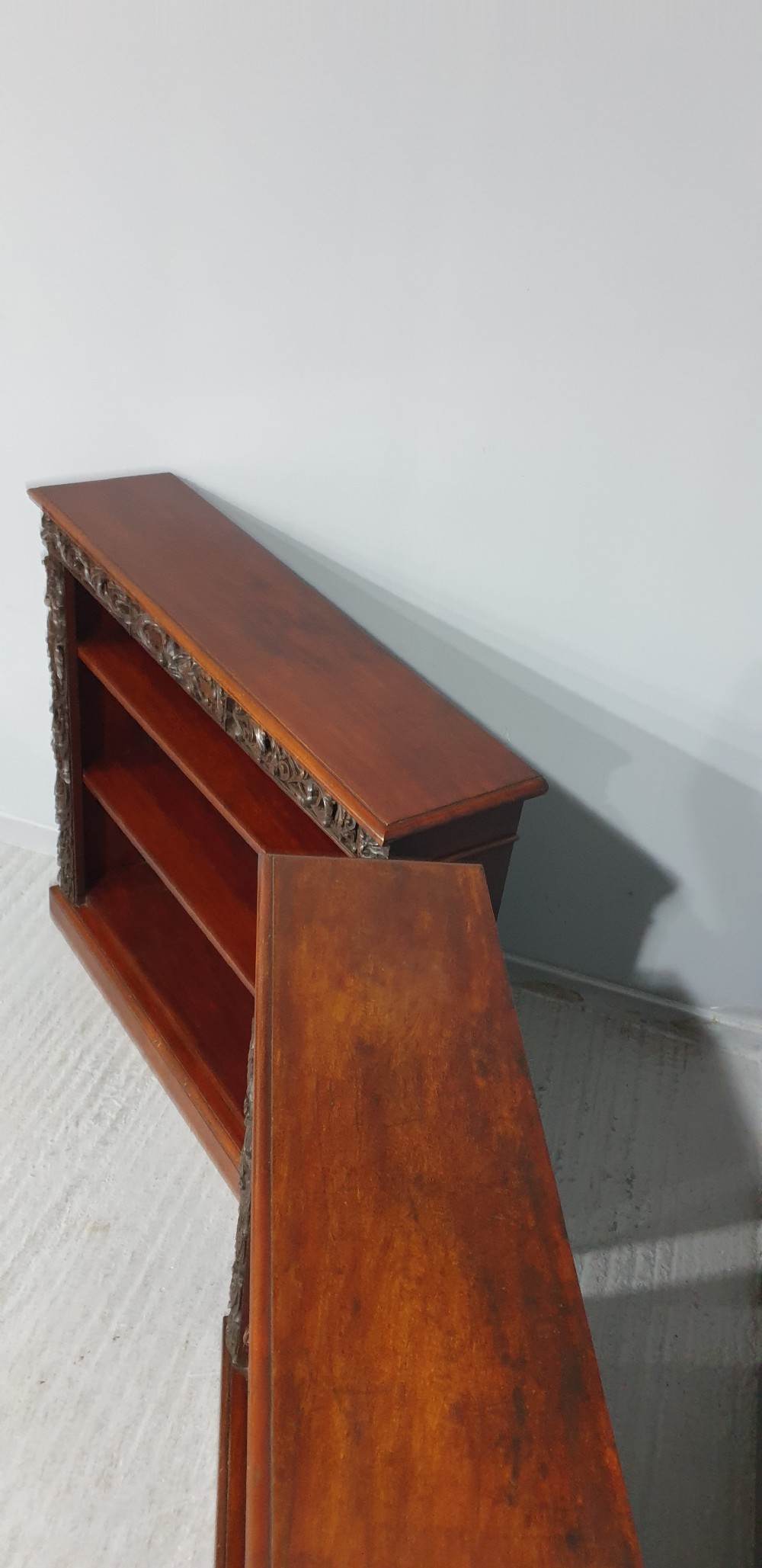 A pair of low mahogany open library bookcases featuring carved friezes, pilasters, and three adjustable shelves on plinth bases. View IX