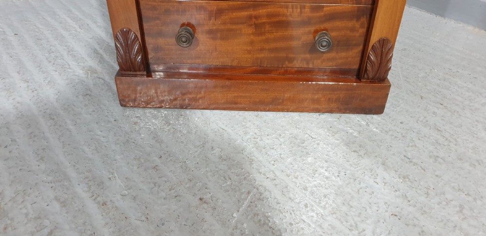 A tall Victorian flame mahogany Wellington chest of drawers featuring eight stacked drawers with turned knobs, flanked by side stiles with carved corbels. View VII
