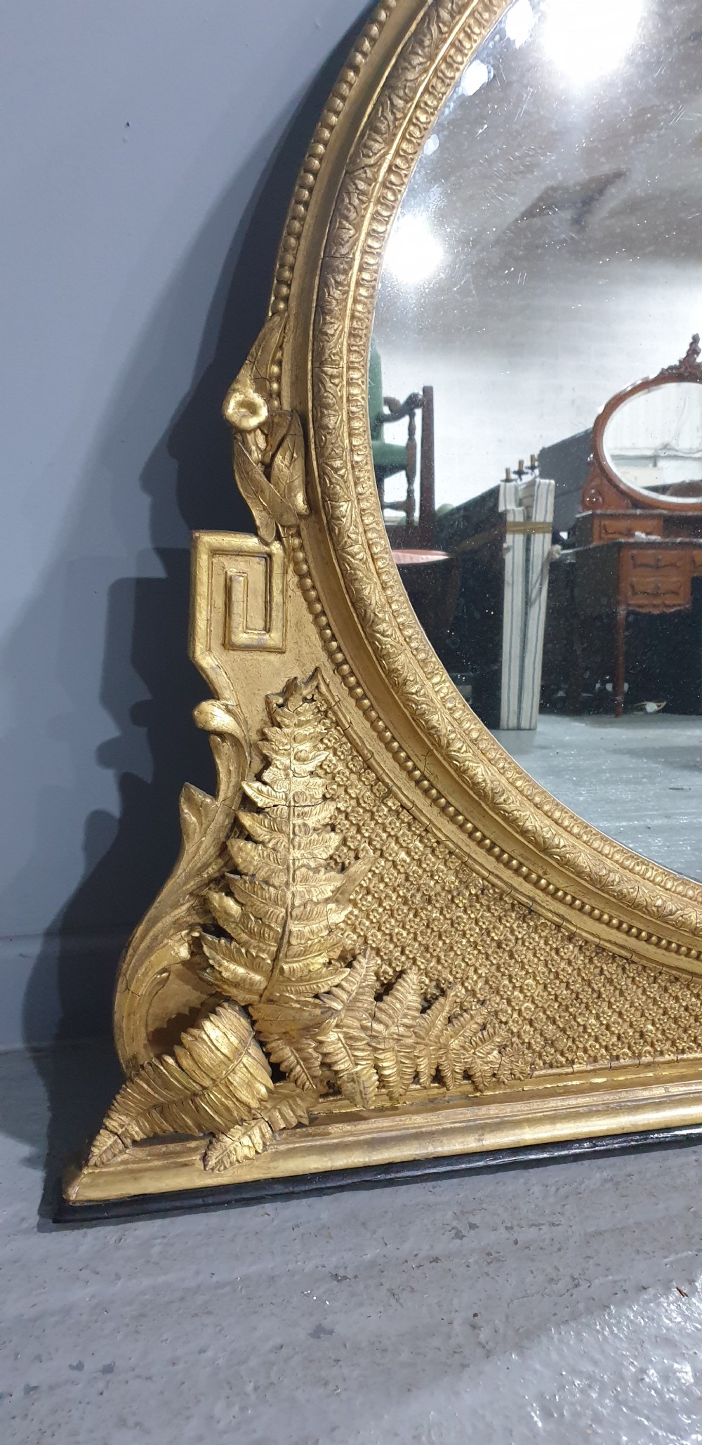 A large High Victorian arched overmantel mirror featuring a gold gilded frame decorated with carved fern leaf motifs, floral cresting, and geometric spandrel detailing. View VII