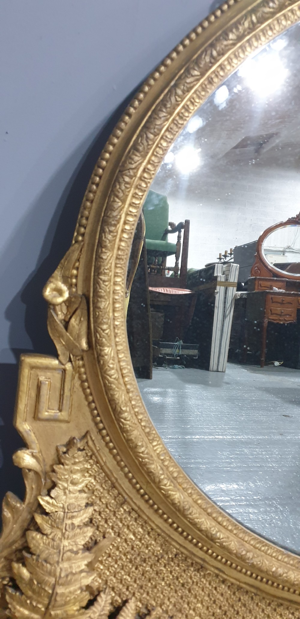 A large High Victorian arched overmantel mirror featuring a gold gilded frame decorated with carved fern leaf motifs, floral cresting, and geometric spandrel detailing. View IX