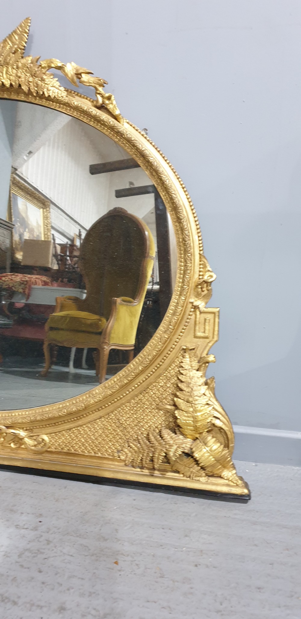 A large High Victorian arched overmantel mirror featuring a gold gilded frame decorated with carved fern leaf motifs, floral cresting, and geometric spandrel detailing. View XIII