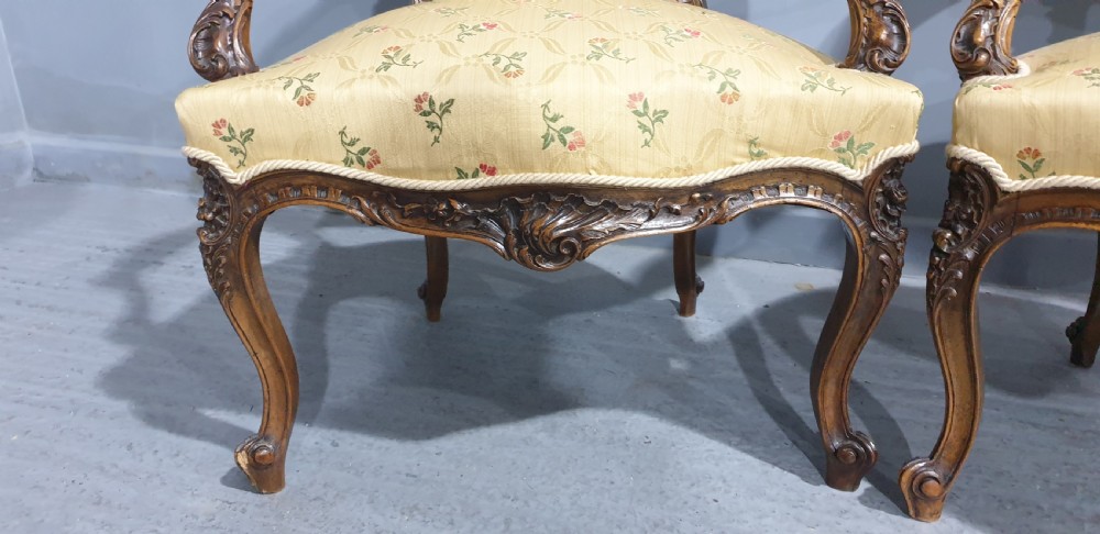A pair of French carved mahogany open armchairs upholstered in patterned yellow floral fabric with cabriole legs. View VI