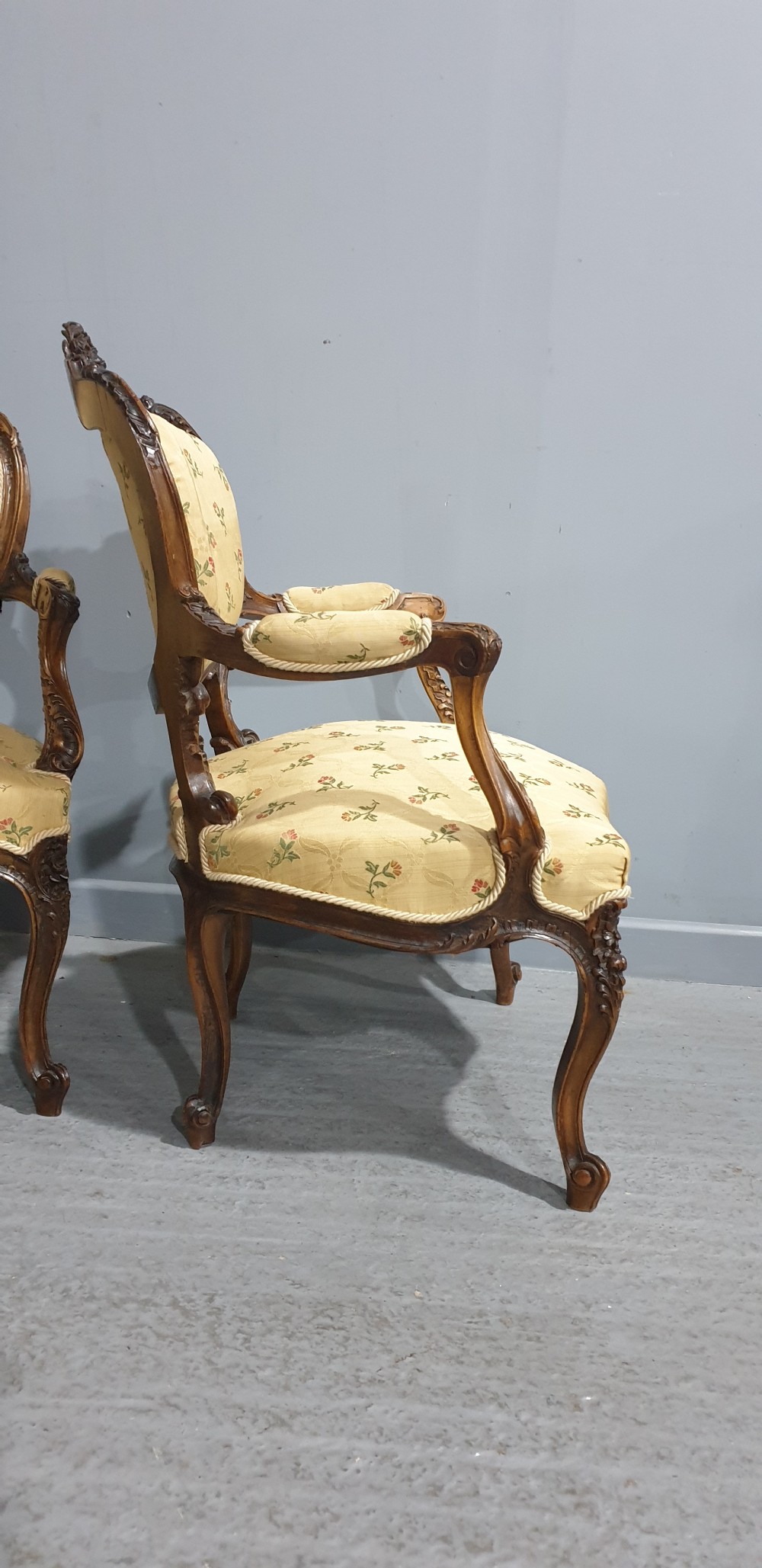 A pair of French carved mahogany open armchairs upholstered in patterned yellow floral fabric with cabriole legs. View IX