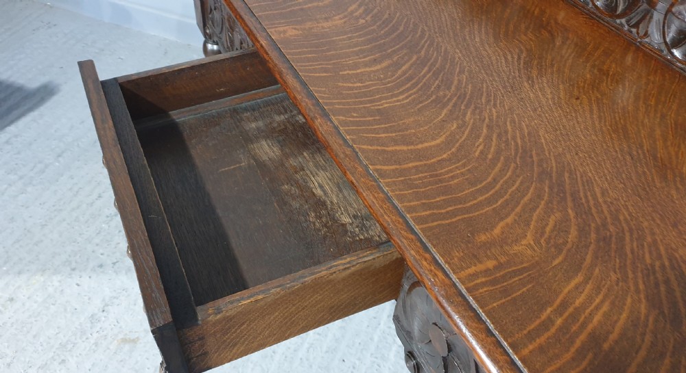 A dark carved oak console table featuring bobbin-turned front legs, a carved rosette frieze, and a low decorative gallery upstand. View VII