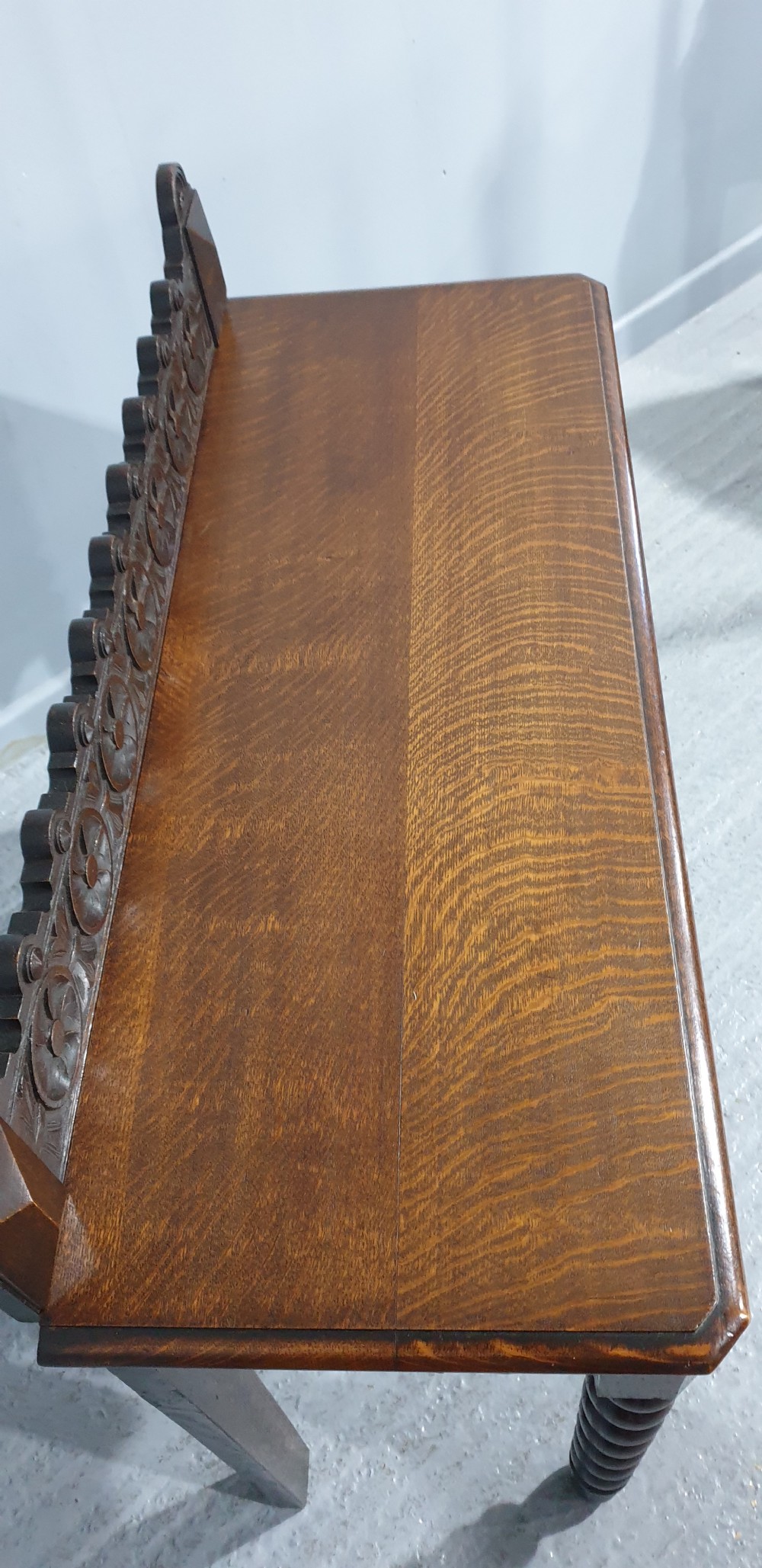A dark carved oak console table featuring bobbin-turned front legs, a carved rosette frieze, and a low decorative gallery upstand. View VIII