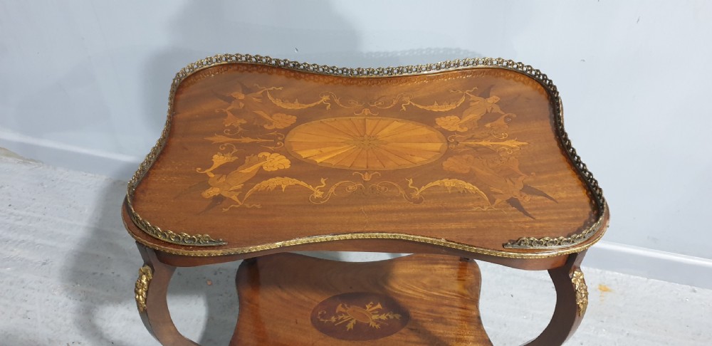 A French-style two-tier occasional table featuring marquetry wood inlays, cabriole legs, brass corner mounts, and a pierced brass gallery rim around the top surface. View II