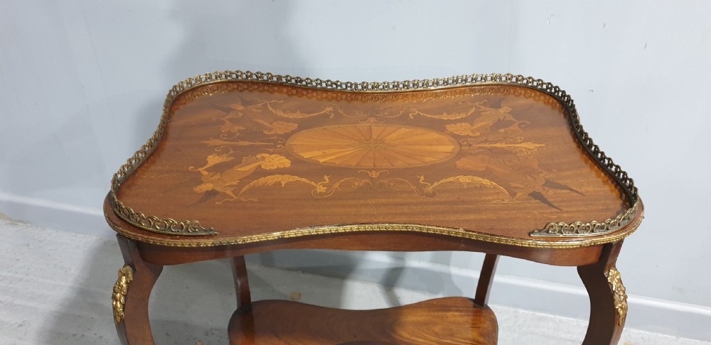A French-style two-tier occasional table featuring marquetry wood inlays, cabriole legs, brass corner mounts, and a pierced brass gallery rim around the top surface. View III