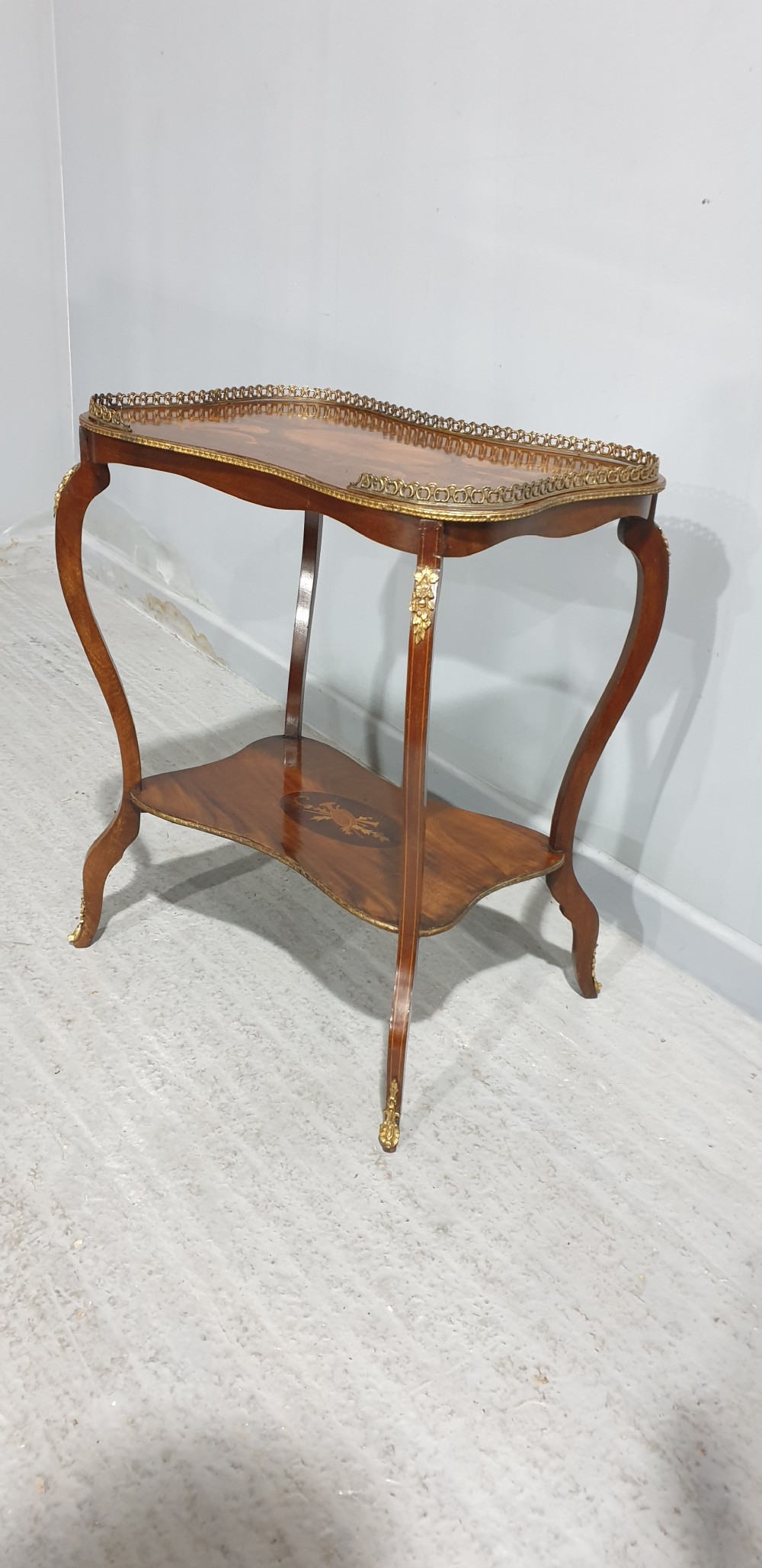 A French-style two-tier occasional table featuring marquetry wood inlays, cabriole legs, brass corner mounts, and a pierced brass gallery rim around the top surface. View VII