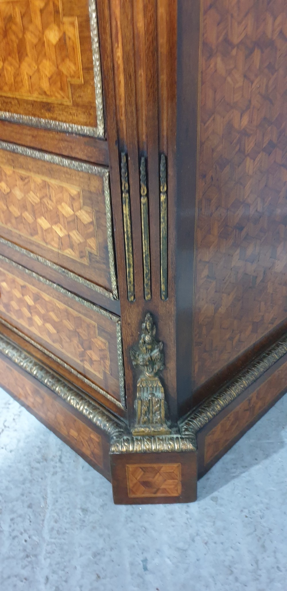 A tall French seven-drawer semainier chest with geometric wood parquetry, gold-toned ornamental mounts, and a white marble top. View X