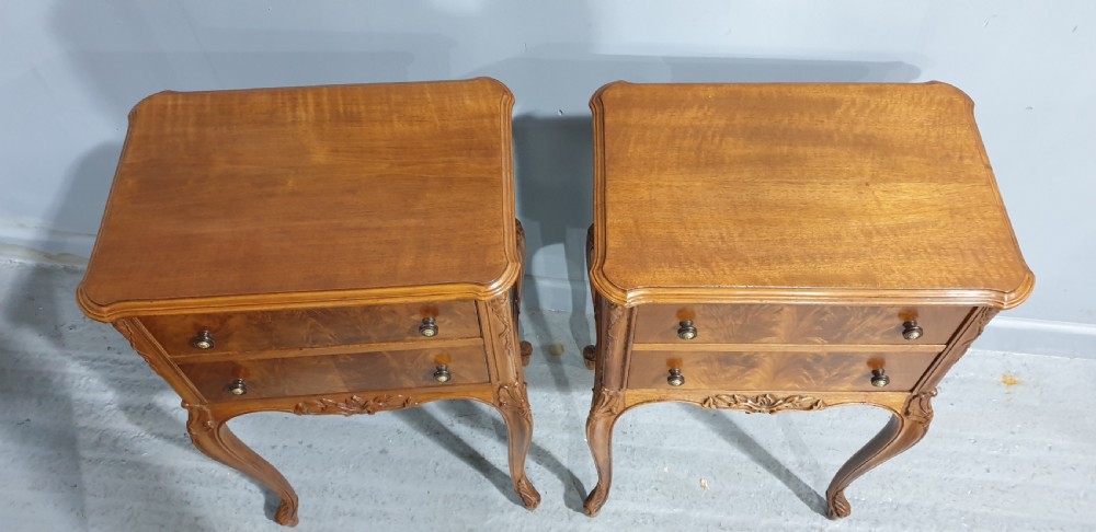 A pair of warm brown walnut bedside chests featuring two drawers with brass knobs, carved aprons, and long cabriole legs. View VIII