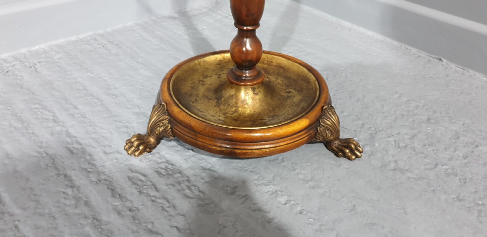 A Victorian turned mahogany stick stand featuring a circular top brass divider ring, a central turned stem, and a round brass drip tray base elevated by brass claw feet. View VI