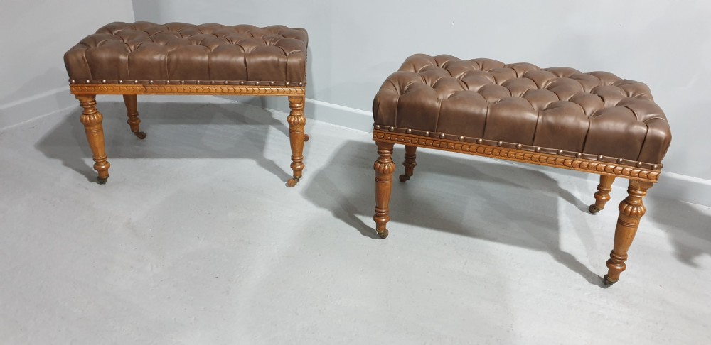A pair of Victorian deep-buttoned brown leather window seats featuring carved turned legs on brass castors with brass stud detailing. View II