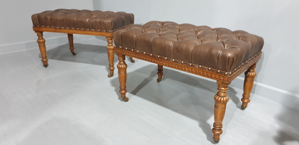 A pair of Victorian deep-buttoned brown leather window seats featuring carved turned legs on brass castors with brass stud detailing. View III