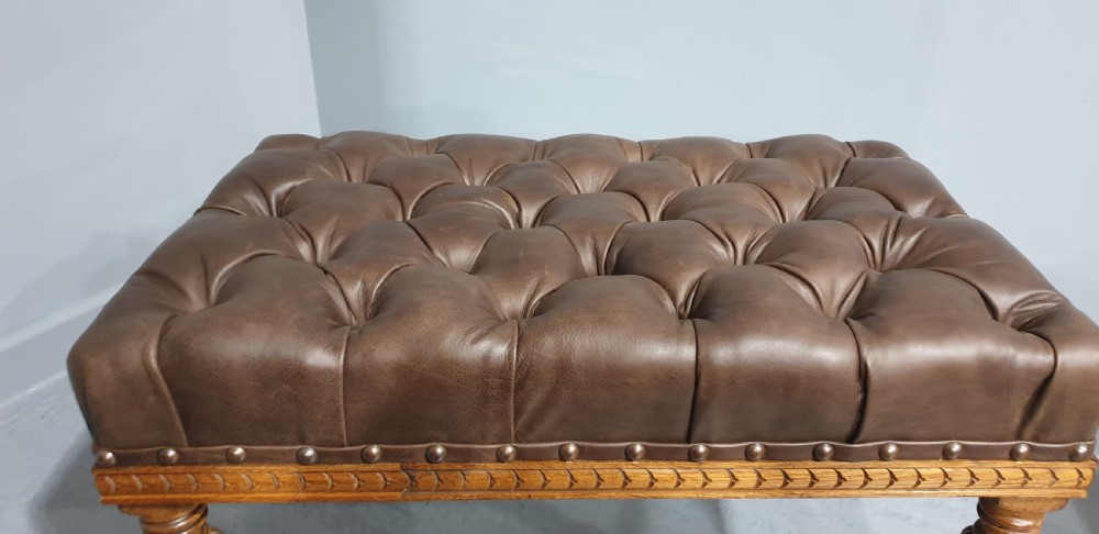 A pair of Victorian deep-buttoned brown leather window seats featuring carved turned legs on brass castors with brass stud detailing. View VIII