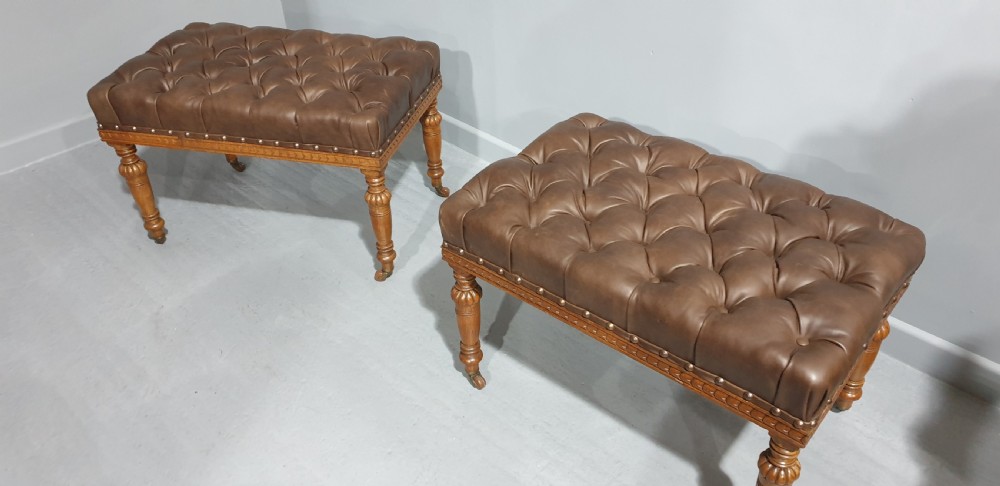 A pair of Victorian deep-buttoned brown leather window seats featuring carved turned legs on brass castors with brass stud detailing. View IX