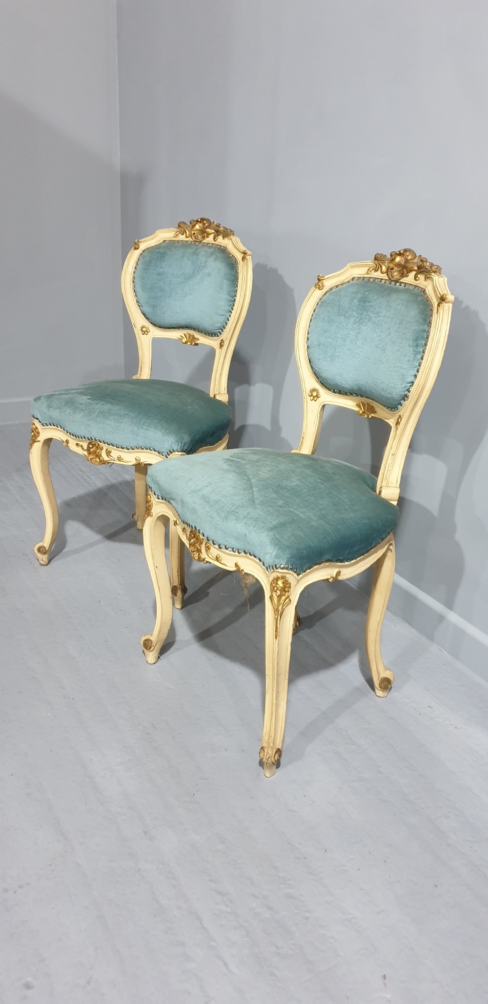 A pair of French Rococo style side chairs featuring cream and gold painted wooden frames with cabriole legs and blue velvet upholstery. View III