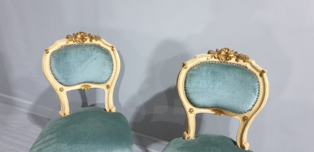 A pair of French Rococo style side chairs featuring cream and gold painted wooden frames with cabriole legs and blue velvet upholstery. View IV