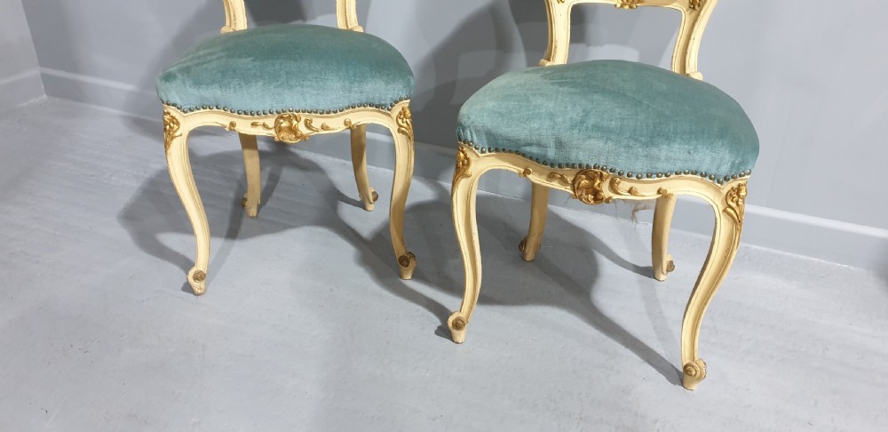 A pair of French Rococo style side chairs featuring cream and gold painted wooden frames with cabriole legs and blue velvet upholstery. View VI