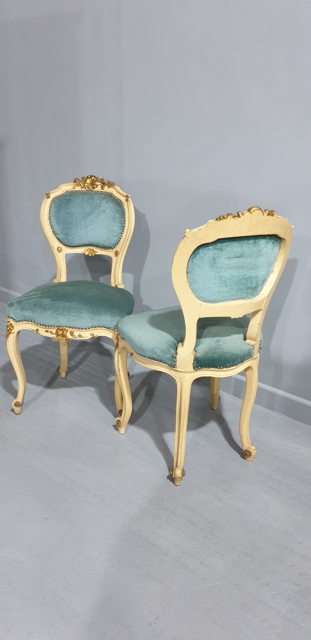 A pair of French Rococo style side chairs featuring cream and gold painted wooden frames with cabriole legs and blue velvet upholstery. View VII
