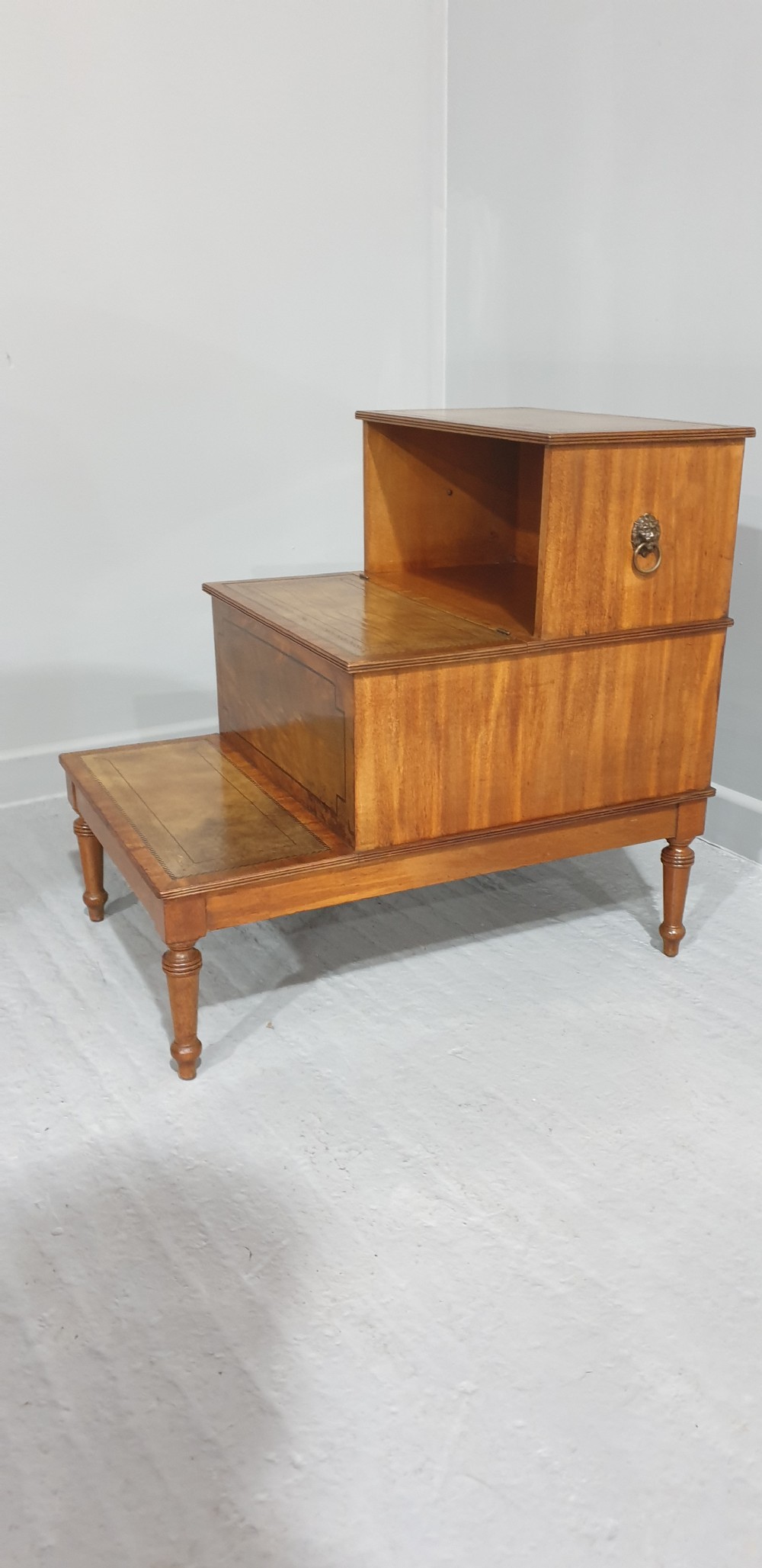 A set of three-tier Victorian mahogany library steps with leather-inset treads, turned legs, and side brass fittings. View II
