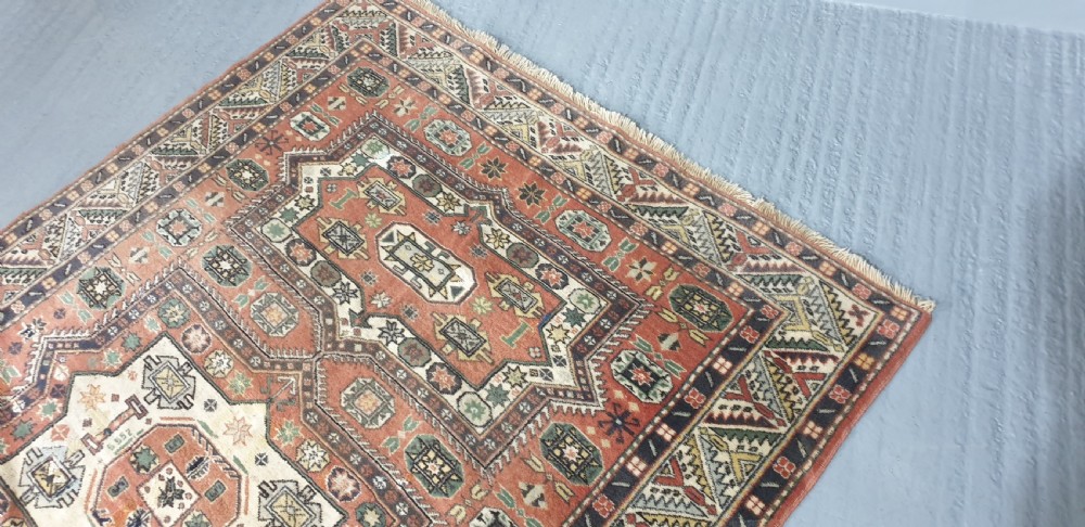 A large hand-knotted Persian wool area rug featuring central geometric medallions in terracotta red, navy blue, green, and cream. View VIII