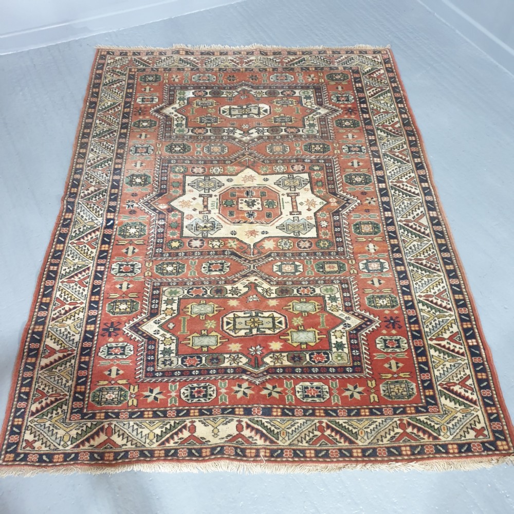 A large hand-knotted Persian wool area rug featuring central geometric medallions in terracotta red, navy blue, green, and cream. View II
